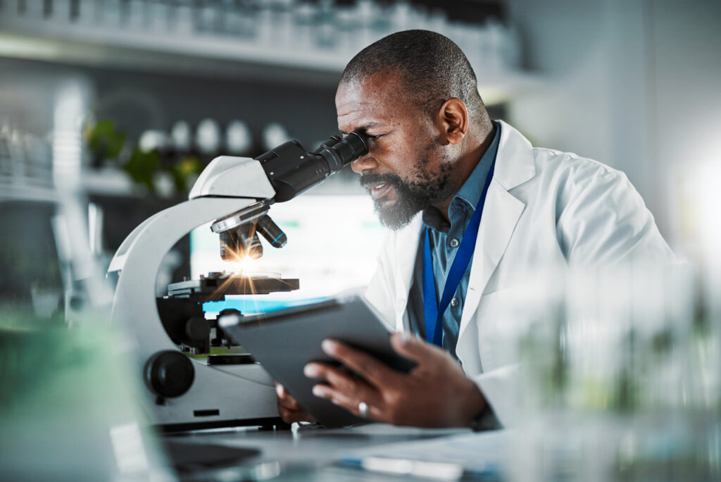 scientist looking into microscope with bright light from slide