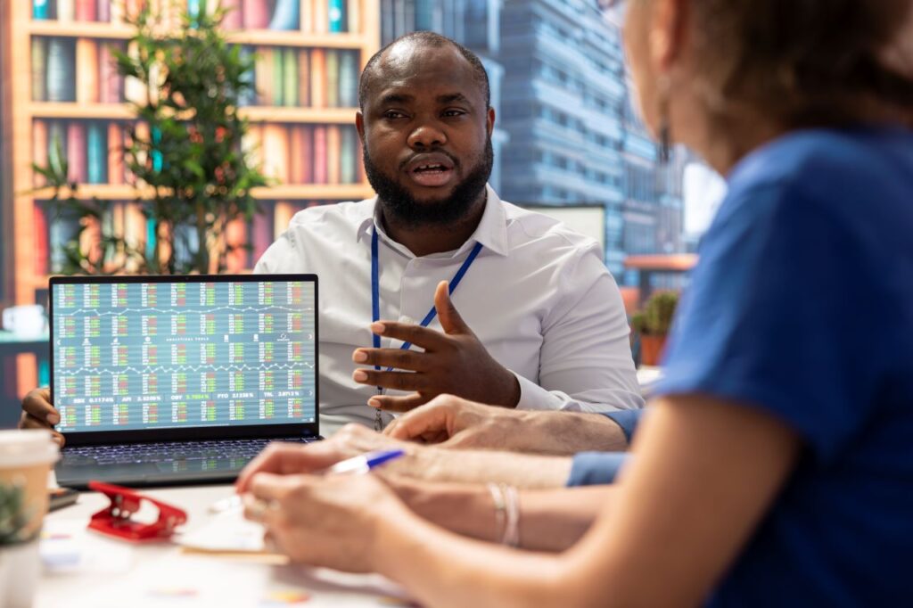 man pointing and talking about stats on a computer