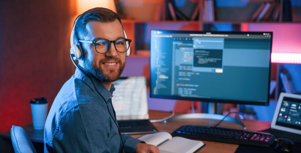 programmer sitting at desk and smiling at camera