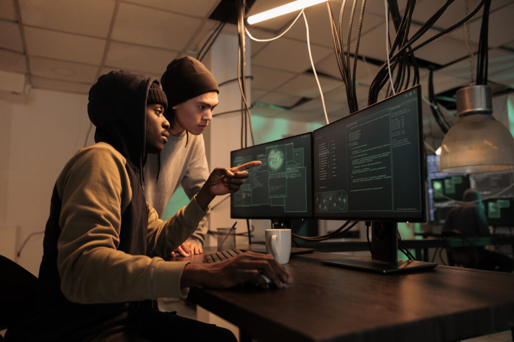 cyber hackers looking at computer screen in dark room