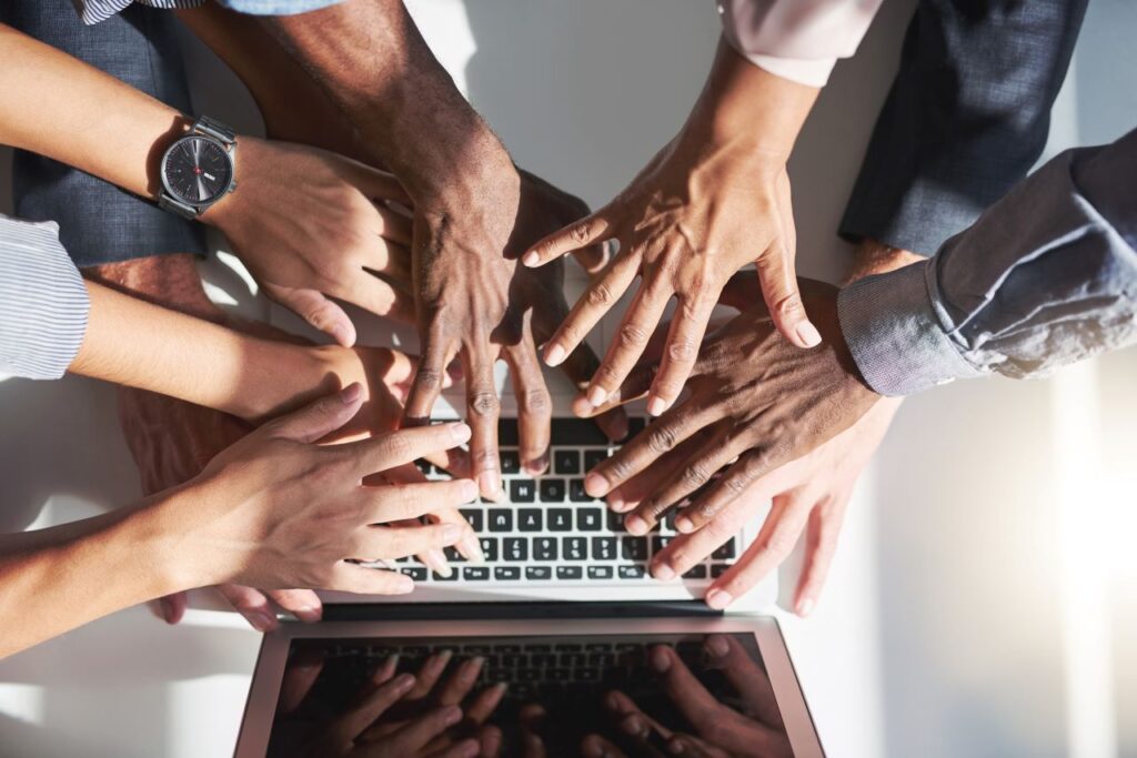 all hands hovering over a laptop together