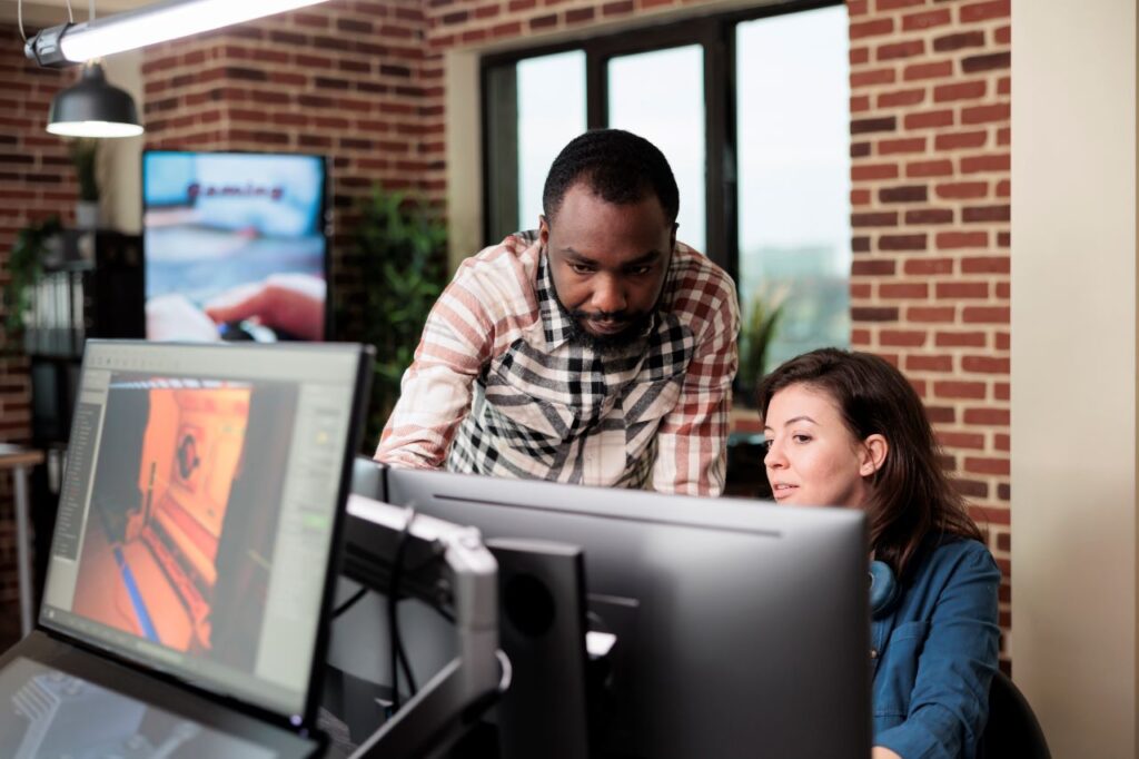 man pointing to monitor with woman co worker