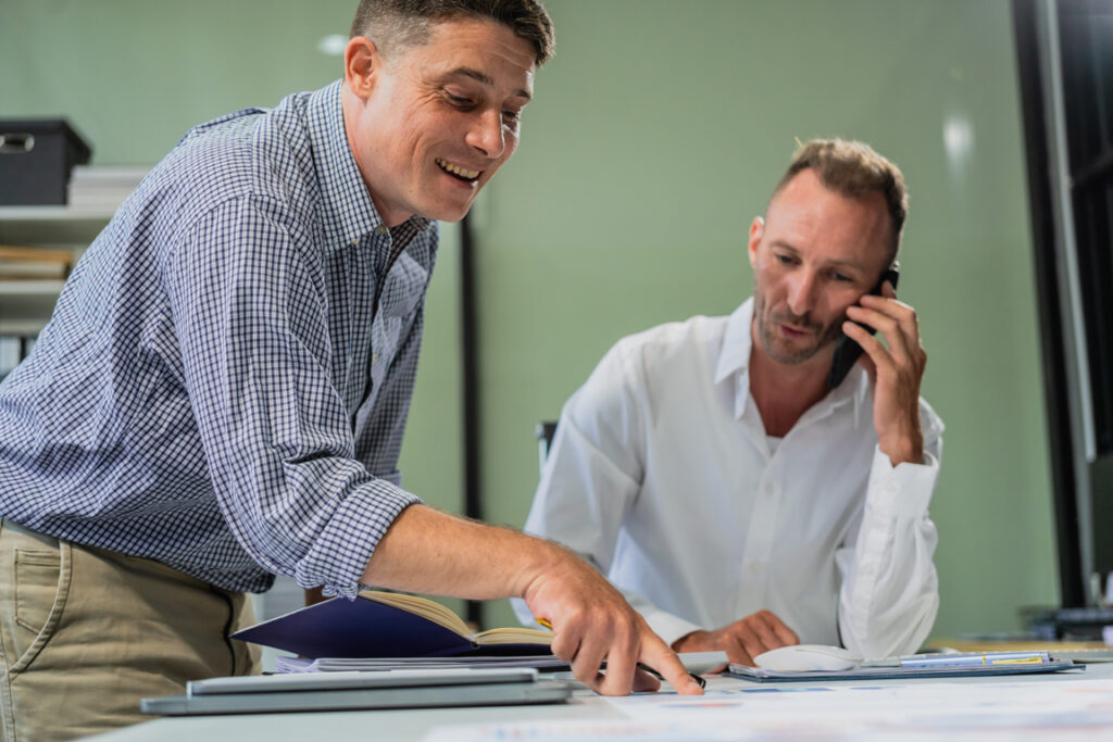 Caucasian middle-aged male businessperson an Italian accountant are seated at a desk, engaging