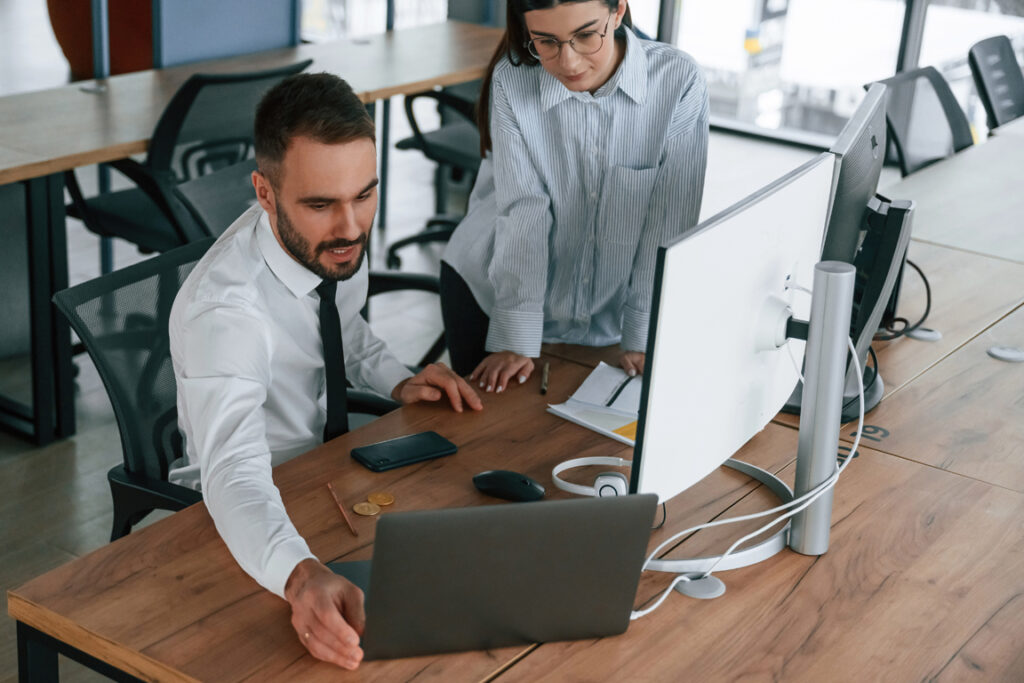 With laptop. Two employees are working in the office together.